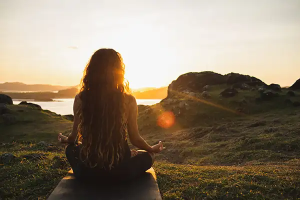 Woman meditating doing yoga at sunrise in the mountains